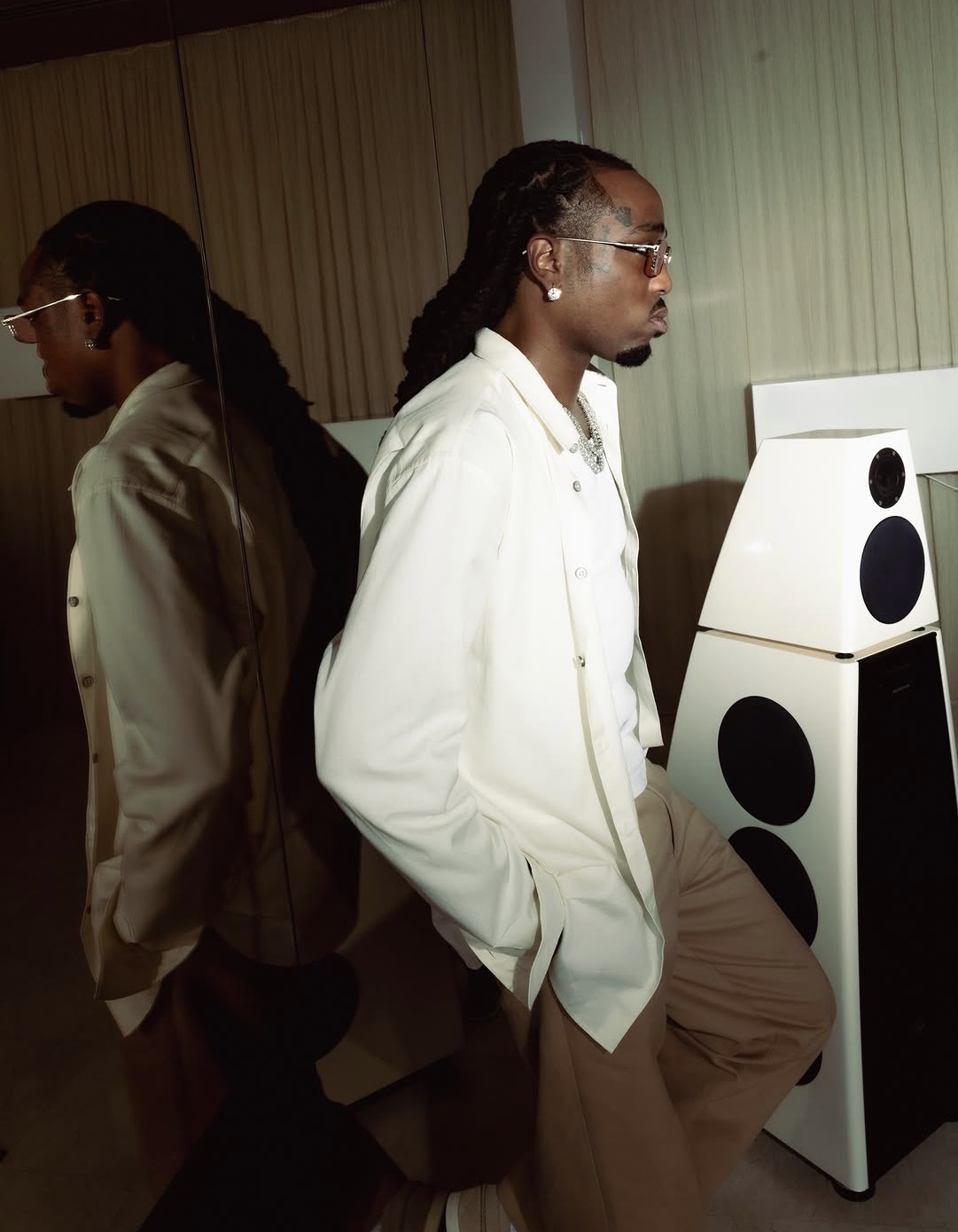Quavo in a cream ensemble beside his reflection